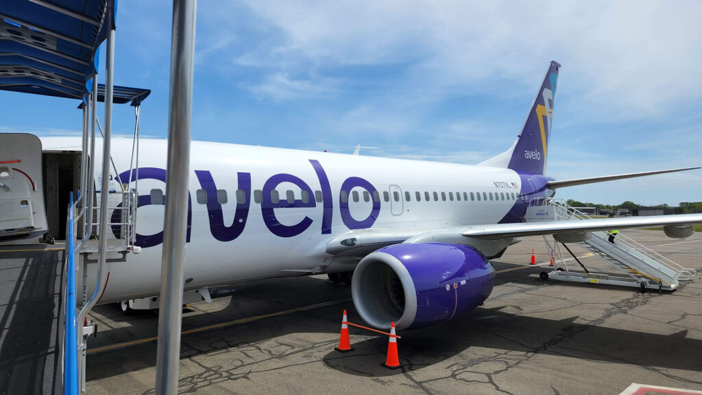 White and purple colored aircraft sitting on the tarmac at an airport.